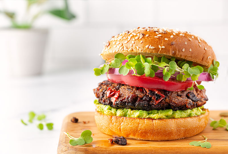 A burger in a bun with tomato and lettuce garnish
