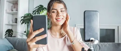 A woman indoors shooting a selfie on her phone