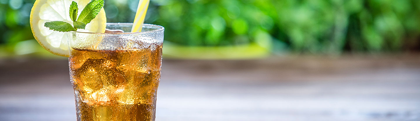 Carbonated lemon drink with straw outside on a sunny day