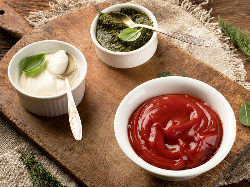 A selection of sauces displayed on a wooden paddle tray
