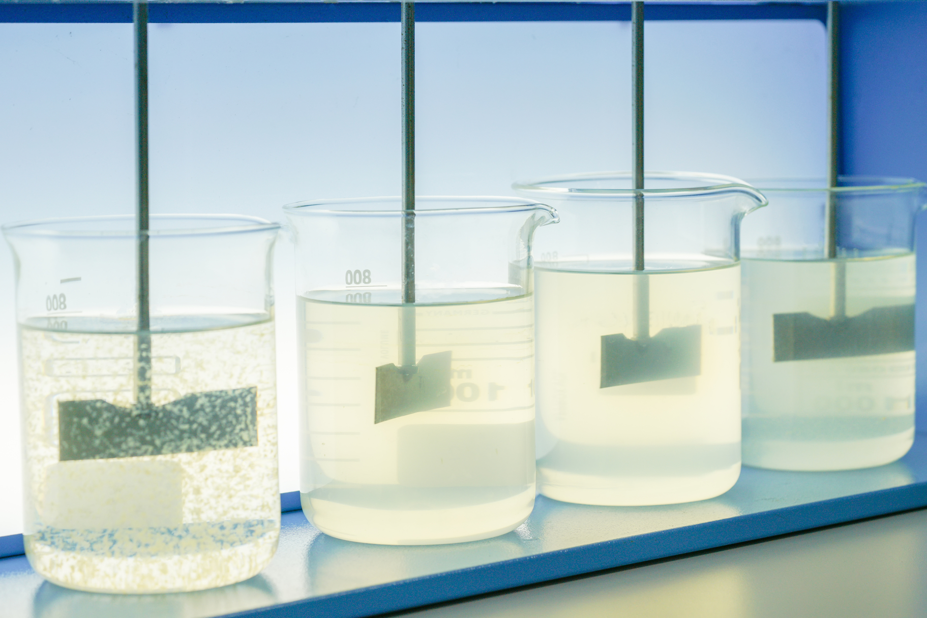 Four glass beakers each one with an increasing amount of flocculating substances