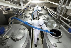 Workers in PPE hose down chemical tanks used in the process of toll manufacturing and blending 