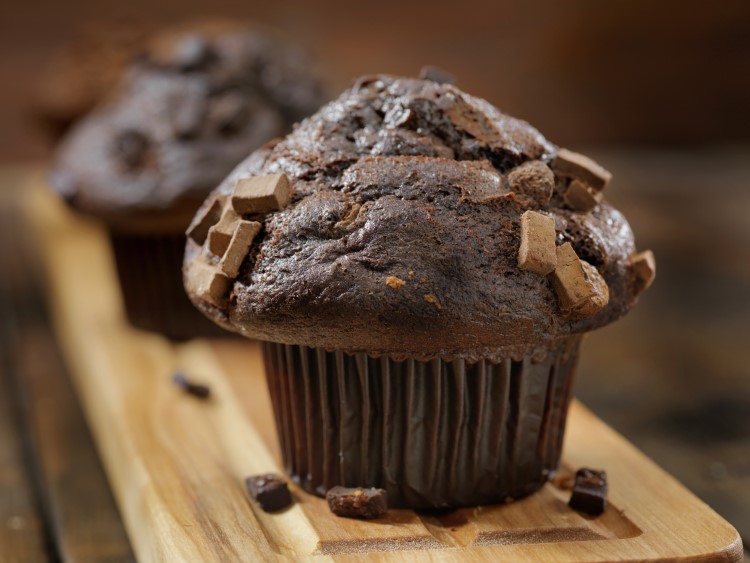 A row of double chocolate chip muffins on a wooden serving tray