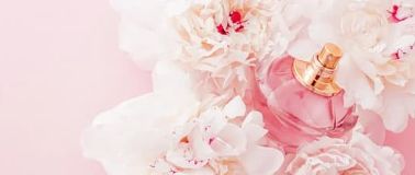Fragrance bottle in bunch of flowers on pink background