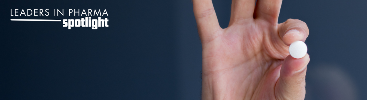 Hand holding a small round prescription medication